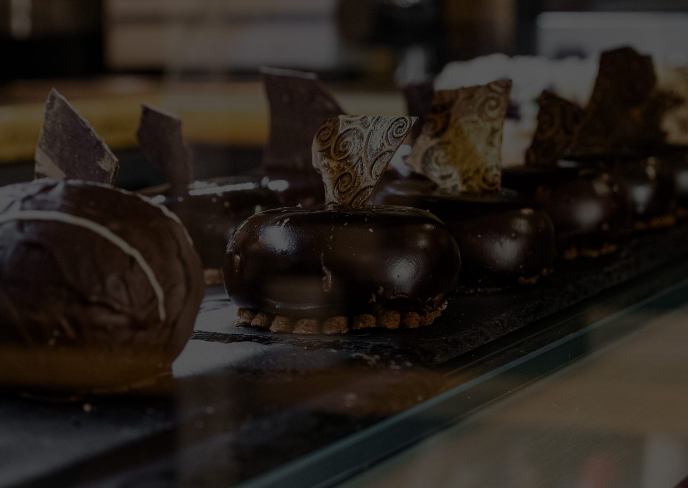 Ein paar Schokoladentörtchen mit goldenen Schokoplättchen als Dekoration in einer Kuchenvirtrine
